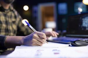 Selective focus of freelancer writing ideas and new code on a notebook to guarantee cyber security. Man managing programs in artificial intelligence and machine learning on a laptop. photo