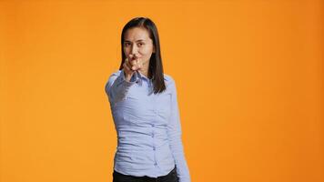 Asian model pointing at the camera in colorful studio, looking into the lens with confidence. Young filipino woman points index finger and standing proud against orange background. photo