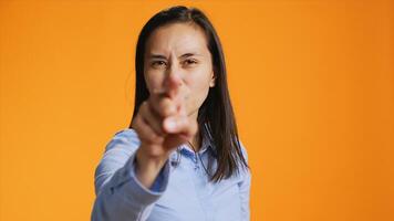 During the shot, pleased filipino girl points index finger at the lens. Confident young woman with calm mood using charm and personality, standing over orange background illustrating stuff. photo