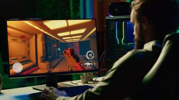 Man in dark living room playing engaging video games on gaming PC at computer desk, chilling after work. Gamer contending against foes in online multiplayer shooter, shooting them with lasers photo