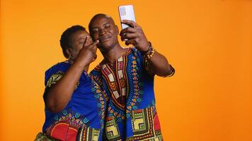 contento africano americano Pareja capturar linda momento en estudio, tomando imágenes en teléfono inteligente y disfrutando ocio actividad. romántico casado personas tomar fotos para recuerdos en teléfono.