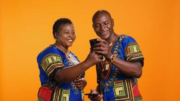 African american couple checking social media network on smartphone app, reading their messages on internet connection. Man and woman using mobile phone to scroll on websites. photo