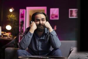 Depressed man looking saddened at TV display while playing videogames, receiving game over screen on gaming console. Gamer putting face in hands, upset after being defeated by enemy players photo