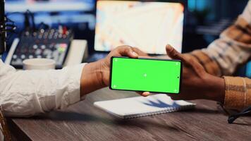 Man invited to podcast watching internet clips on green screen phone with host in apartment studio. Guest reacting to videos on mockup smartphone during online comedy show photo