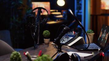 Panning shot of desk in home production studio with podcast equipment technology recording sound and 3D animations running on laptop screen. Professional broadcasting space in apartment photo