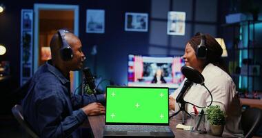 Focus on green screen laptop in front of show host recording podcast, using analog mixer in studio. Mockup notebook and man setting up audio devices in live broadcast for flawless sound quality photo