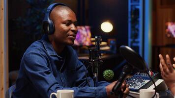 Podcast presenter using professional audio equipment to ensure high sound quality during live discussion with guest, streaming it for audience, broadcasting from personal home studio photo