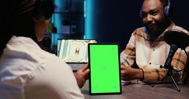 Online show host holding green screen tablet while listening to guest opinion on current events during live broadcast for social media platforms. Mockup device used by influencer recording podcast photo