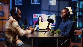Guest on internet podcast telling interesting story to journalist asking him questions, captivating fans watching. Man in studio sharing facts, surrounded by sound engineering equipment photo