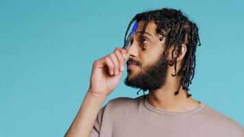 Middle Eastern man thinking, tapping pen to forehead, coming up with idea concept. Pensive person contemplating, doing introspection, having eureka moment, studio background, camera B close up photo