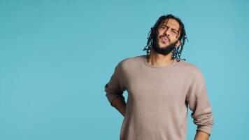 Hurt Middle Eastern man screaming from pain, suffering from back injury, having health problems. Injured BIPOC person feeling uncomfortable ache, yelling, studio background, camera A photo