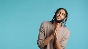 Pious Middle Eastern man praying to his god, asking for forgiveness, feeling desperate. Spiritual BIPOC man doing worship hand gesturing, confessing, begging for pardon, studio background, camera A photo