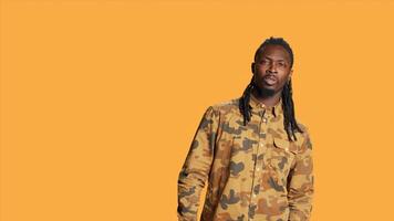 Optimistic person showing okay symbol on camera, smiling and expressing positivity with like sign over orange background. Pleased cheerful guy acting satisfied and relaxed in studio. photo