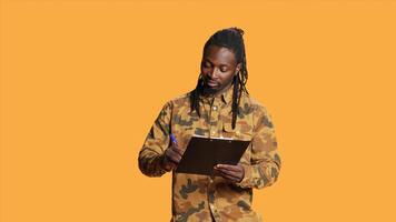African american guy looks at checklist on clipboard files, taking notes and preparing with a lot of information on papers. Young man writing something on his weekly organizer, plan survey. photo