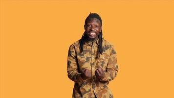 Amazed african american adult saying wow in studio feeling surprised by something in front of him. Cheerful excited man with dreads smiling on camera, shocked over orange background. photo