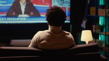 Person relaxing on couch watching VOD channel on large television set in living room. Zoom in shot on cord cutter entertained by streaming service program broadcasted on smart TV in home theatre photo