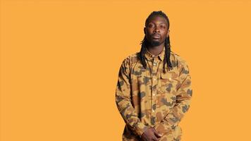 African american guy with cool shirt posing on camera, smiling and feeling optimistic over orange background. Young person being cheerful and relaxed in studio, expressing positivity. photo