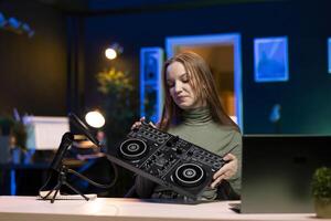 Young artist filming DJ mixing tutorial in apartment studio, showing examples of sampling on sound controller to viewers. Entertainer showing modern musical equipment to subscribers in living room photo