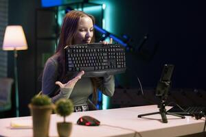 Young influencer testing mechanical keyboard while doing review in personal studio to see if price is justified. Gen Z media star showcasing computer peripheral features to audience photo
