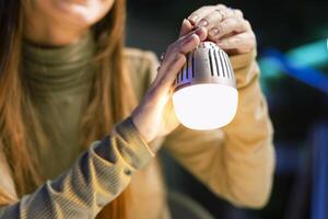 Young influencer filming review of light bulb able to change into different colors, close up shot. Content creator showcasing smart home automation technology in apartment studio photo