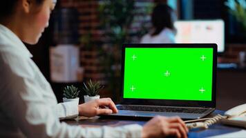 Worker looks over statistical financial data on chroma key laptop, researching data for company project. Businesswoman analyzing stock market figures and charts on mockup device photo