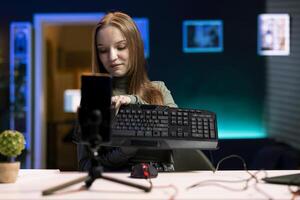 Content creator typing on mechanical keyboard while doing review in personal studio to see if price is justified. Technology guru showcasing computer peripheral features to fans photo