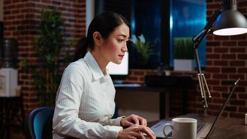 Businesswoman transcribing information from laptop to notepad, doing tasks for team project in office overnight. Worker working late at night, writing down data from computer screen photo
