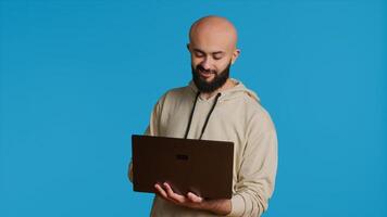 Middle eastern man works with cyber security on laptop, trying to do some software programming and report bugs. Young adult operating as a system developer in studio. Camera 1. photo