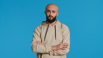 Middle eastern person acting impatient over background, tensed man waiting for something with arms crossed on camera. Arab male model being serious and punctual. Camera 1. photo