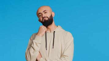 Middle eastern person thinking about a thing on camera, acting pensive and puzzled while trying to make a decision. Arab guy acting thoughtful and unsure about a question. Camera 2. photo