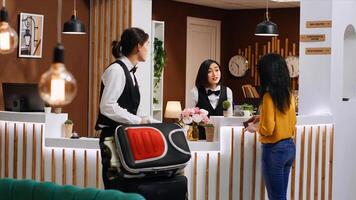 Asian client finishing with check in process at front desk, receiving passport and access key card to see room reservation. Bellboy providing luxury concierge services for middle aged guest. photo