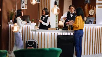 Women going through registration process at front desk, hotel staff team checking passport information for registration. Travelers signing reservation forms for accommodation. Handheld shot. photo