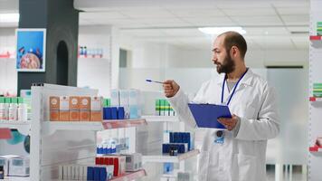 Pharmacy worker writing every medical product on inventory, creating long list with all pharmaceutics and medicaments in drugstore. Pharmacist ensuring variety of healthcare supplies. Camera 2. photo