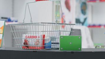 Basket filled with medicaments and a box with greenscreen layout at pharmacy cash register counter. Empty drugstore having pharmaceutics and package with isolated copyspace mockup. photo