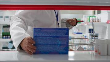 pov de médico empleado colocación todas medicamentos en cajas o botellas en monitor a farmacia, Ayudar con productos repoblar. hombre trabajando en un farmacia, abastecimiento estantería con medicamento. trípode disparo. foto