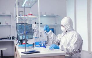 Lab scientist uses micropipette while examining sample doing drug development. Chemist in modern laboratory doing research using dispenser during global epidemic with covid-19. photo