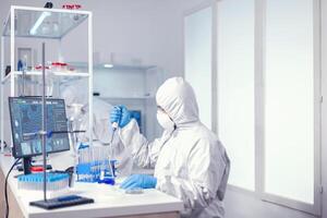 Doctor taking carefully sample from test tube using automatic pipette Chemist in modern laboratory doing research using dispenser during global epidemic with covid-19. photo