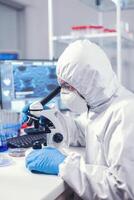 Scientist using modern laboratory equipment dressed in protection against covid19. Virolog in coverall during coronavirus outbreak conducting healthcare scientific analysis. photo