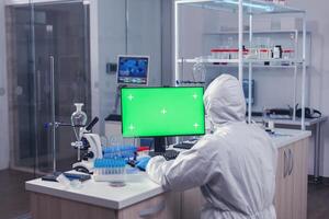 Medica staff using computer with green mok up in scientific laboratory. Team of microbiologists doing vaccine research writing on device with chroma key, isolated, mockup display. photo