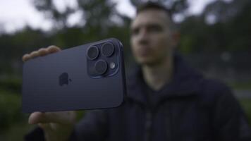 UK, London - September 15, 2023. Man takes pictures on new iPhone. Action. Apple's logo on new iPhone 15 pro. Shooting on new iPhone 15 pro in nature photo