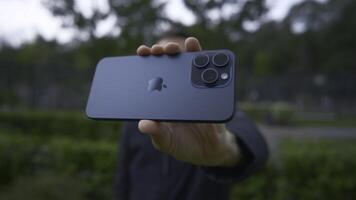 UK, London - September 15, 2023. Man takes pictures on new iPhone. Action. Apple's logo on new iPhone 15 pro. Shooting on new iPhone 15 pro in nature photo