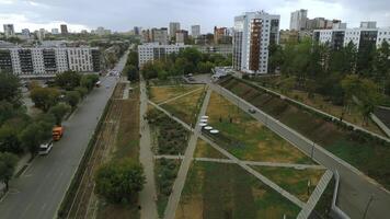 Top view of park alley in residential area of city. Clip. View of city with residential buildings and park alley. Beautiful landscape of park alley in urban landscape with buildings photo