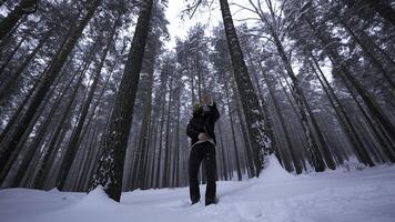 disparo acortar en invierno bosque. medios de comunicación. elegante hombre es golpecitos en invierno bosque. hombre se mueve elegantemente y raps en invierno bosque. música vídeo foto