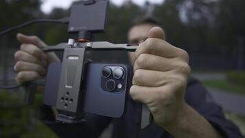 UK, London - September 15, 2023. Man professionally shoots on phone with stabilizer. Action. Cinematic shooting on new iPhone 15 pro. Shooting with stabilizer for cinematic effect with new iPhone 15 photo