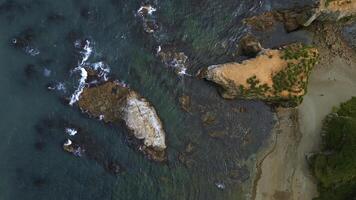 Top view of beautiful wild coast with rocks in water. Clip. Coastline with rocks and waves near shore. Inspiring nature of sea coast with variety of rocks photo
