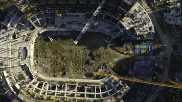 Vertical top view of construction of circular building. Stock footage. Construction site of building near parking lot in city center. Construction of stadium in center of residential city on sunny photo