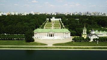 Palace with pond on background of modern city. Creative. Top view of beautiful historical complex on sunny summer day. Palatial buildings with garden and pond with contrast of modern city on horizon photo