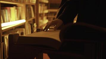 Close-up of mysterious man opening large book. Stock footage. Man opens book in dark library with flashing light. Secret society with mysterious books in night library photo