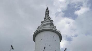 Sri Lanka, Kandy - July 29, 2023. Ambuluwawa Tower Sri lanka. Action. View from below of white spiral tower on background sky. Beautiful towering tower with twisted steps on facade photo