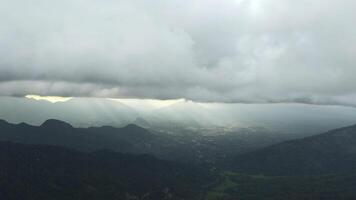 hermosa ver de montaña verde Valle con nubes y luz de sol. acción. pintoresco paisaje de verde montañas y bajo nubes con Dom rotura a través de. del sol rayos en horizonte en verde montaña foto